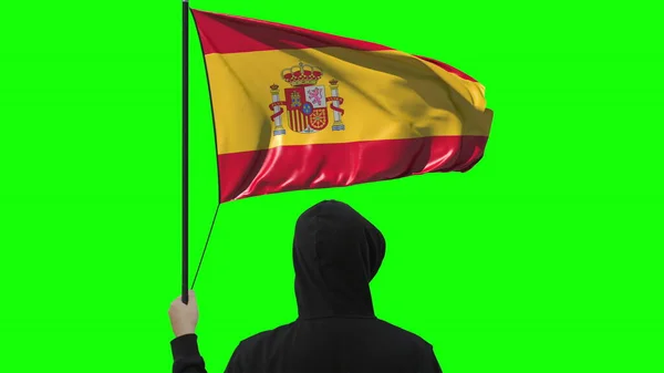 Bandera ondeante de España y hombre desconocido vestido de negro, aislado sobre fondo verde — Foto de Stock
