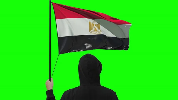 Zwaaiende vlag van Egypte en onbekende man in het zwart, geïsoleerd op groene achtergrond — Stockfoto