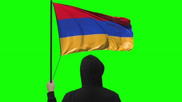 Прапор Вірменії і незнайомий чоловік у чорному, ізольованому на зеленому тлі. — стокове фото