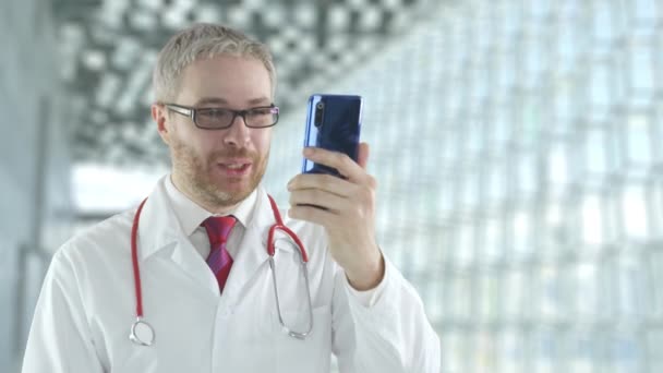 Doctor utilise son smartphone moderne pour un appel vidéo avec un patient — Video