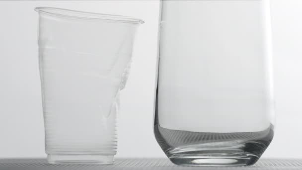 Згорнувши пластикову чашку і склянку на світлому фоні. Концепція стійкості пластмас — стокове відео