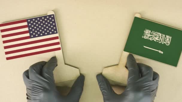 Флаги США и Саудовской Аравии из переработанной бумаги на картонном столе — стоковое видео