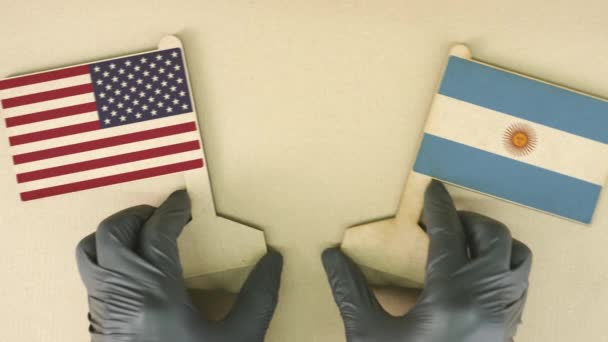 Memegang bendera Amerika Serikat dan Argentina yang terbuat dari kertas daur ulang di meja kardus — Stok Video