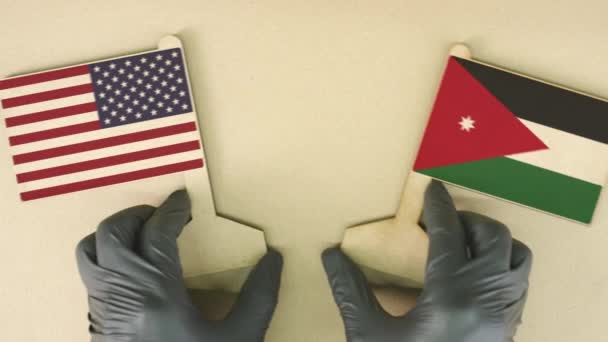 Bandiere degli Stati Uniti e della Giordania in carta riciclata sul tavolo di cartone, vista dall'alto verso il basso — Video Stock