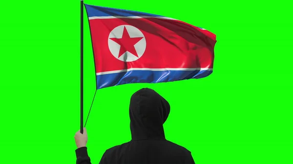 Flagge Nordkoreas schwenkend und unbekannter Mann in schwarz, isoliert auf grünem Hintergrund — Stockfoto