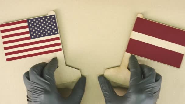 Флаги США и Латвии из переработанной бумаги на картонном столе — стоковое видео