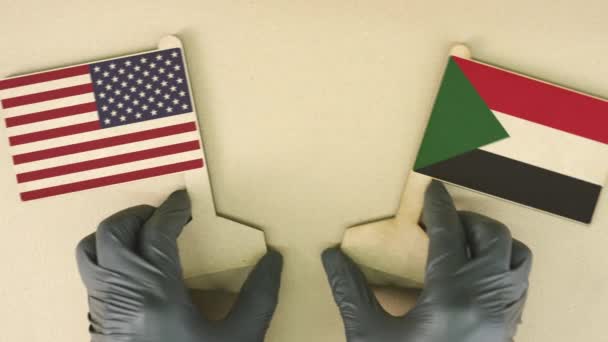 Banderas de Estados Unidos y Sudán de papel reciclado en la mesa de cartón, vista de arriba hacia abajo — Vídeos de Stock