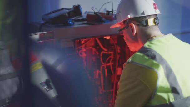 Förvirrad servicetekniker som arbetar med trasig elektrisk utrustning i industrirobotskåp — Stockvideo
