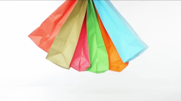 Guante de mano en blanco pone muchas bolsas de papel de color sobre la mesa, concepto de compras — Vídeos de Stock