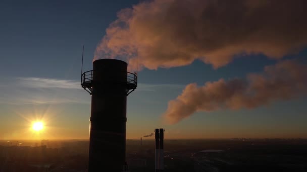 Ilmansaasteet teollisuussavun pinot auringonlaskun taustalla taajama-alueella, ilmakuva — kuvapankkivideo