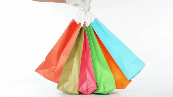 Colocando um monte de sacos de papel de compras a cores sobre a mesa no fundo branco — Fotografia de Stock