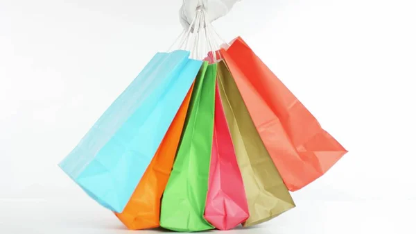 Mão coloca muitos sacos de compras a cores sobre a mesa — Fotografia de Stock