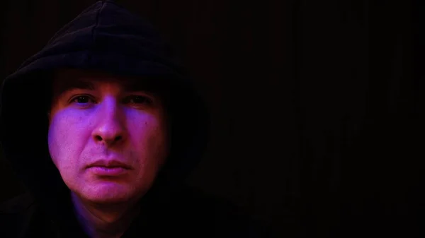 Portrait of a calm caucasian man wearing black hood with police strobe flash reflections on the face. Crime related shot — Stock Photo, Image