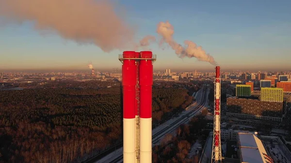 Аэросъемка горизонта Москвы за красно-белыми промышленными дымовыми трубами в зимний вечер, Россия — стоковое фото