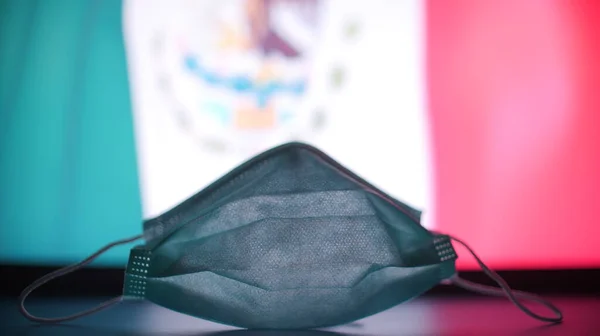 Mascarilla médica contra bandera de México. Concepto de brote COVID-19 — Foto de Stock