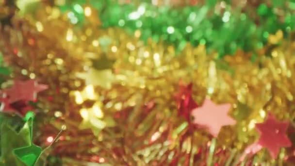 Макро ляльковий знімок блискучих золотих, червоних і зелених гірлянд мішури на Новий рік і Різдво — стокове відео