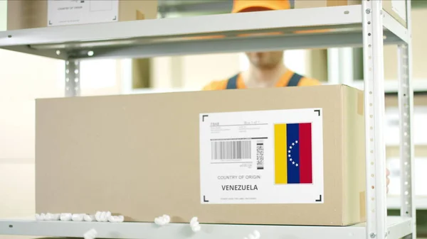 Il lavoratore del magazzino mette un cartone con merci dal Venezuela — Foto Stock