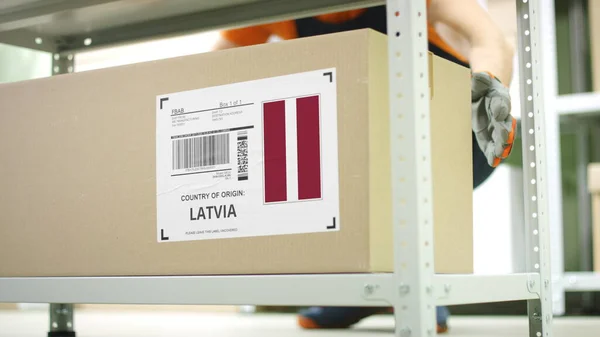 Pracownik zabiera karton z towarami z Łotwy na półce — Zdjęcie stockowe