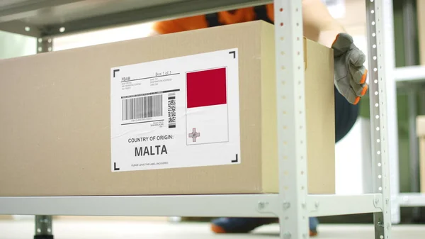 Pracownik zabiera karton z towarami z Malty na półce — Zdjęcie stockowe