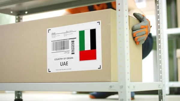 Trabalhador tira uma caixa com produto dos Emirados Árabes Unidos na prateleira — Fotografia de Stock