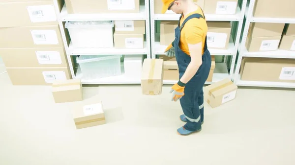 Un ouvrier d'entrepôt négligent dépose un colis endommagé sur le plancher de stockage — Photo