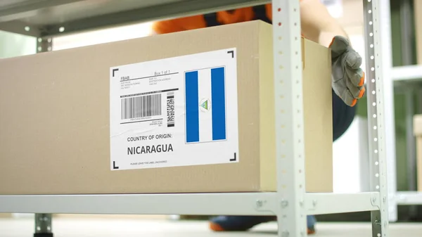 Lavoratore porta via un cartone con merci dal Nicaragua sullo scaffale — Foto Stock