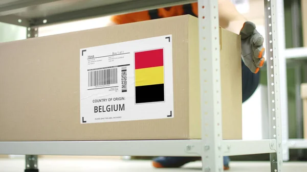 Zaměstnanec skladu odnese karton se zbožím z Belgie — Stock fotografie