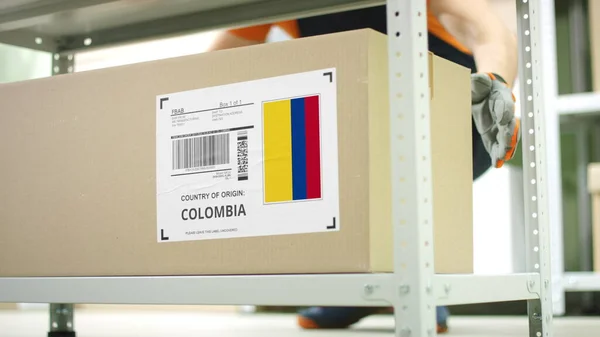 Pracownik magazynu zabiera karton z towarami z Kolumbii — Zdjęcie stockowe