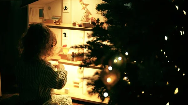 Девушка играет с кукольным домиком дома в новогоднее время — стоковое фото