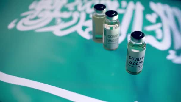 Φιαλίδια με εμβόλιο COVID-19 και σημαία Σαουδικής Αραβίας — Αρχείο Βίντεο