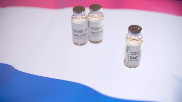 COVID-19ワクチンでガラス瓶とオランダの旗 — ストック動画