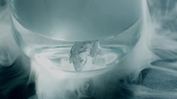 Hielo seco hirviendo o dióxido de carbono congelado en un vaso de agua, disparo en cámara lenta de primer plano — Vídeo de stock