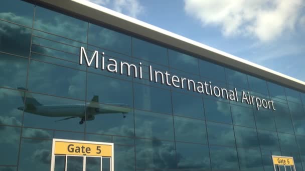 Avión despegue reflejándose en las ventanas con el texto del Aeropuerto Internacional de Miami — Vídeos de Stock