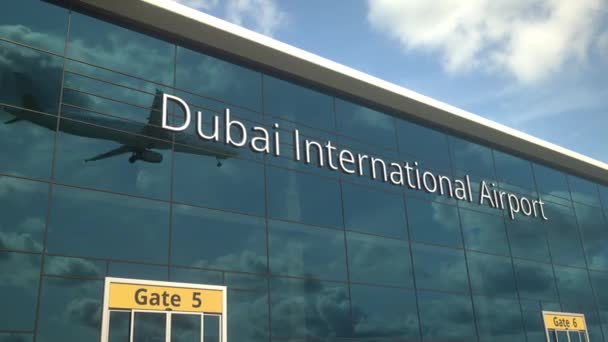 Landeflugzeug spiegelt sich in den modernen Fenstern mit Text vom Dubai International Airport — Stockvideo