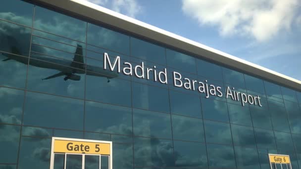 Landning flygplan speglar i de moderna fönstren med Madrid Barajas Airport text — Stockvideo