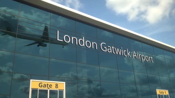 Landung eines Passagierflugzeugs spiegelt sich in den Fenstern mit Text vom Flughafen London Gatwick — Stockvideo