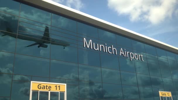 Avión de aterrizaje refleja en las ventanas modernas con el texto del aeropuerto de Munich — Vídeo de stock