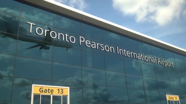 Samolot lądowania odbija się w nowoczesnych oknach z tekstem Toronto Pearson International Airport — Wideo stockowe