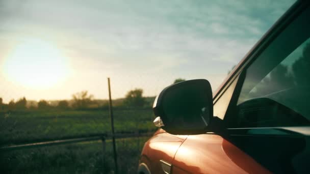 Een geparkeerde rode auto in prachtige zomer zonsondergang landschap — Stockvideo