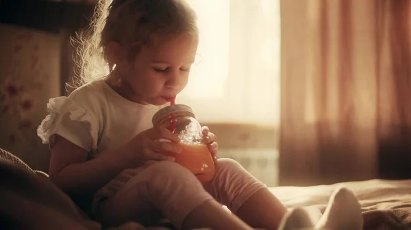Menina loira feliz beber suco de laranja com uma palha — Fotografia de Stock