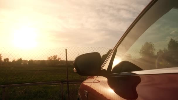 Czerwony samochód w pięknej letniej scenerii zachody słońca za drucianym ogrodzeniem — Wideo stockowe