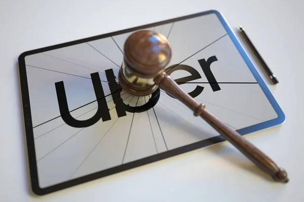 Kaputtes Logo und Richtergabel — Stockbild Das Logo von UBER auf dem Bildschirm des Tablet-Computers, der von Richtern getroffen wurde. Gerichtsbezogene redaktionelle 3D-Darstellung — Stockfoto