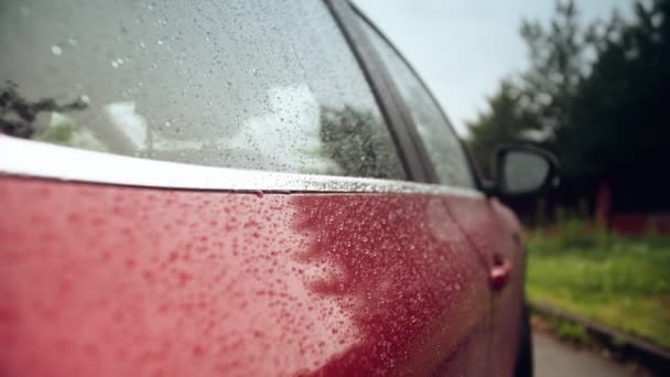 Rain drops on the side a red car on a rainy day — Stock Video