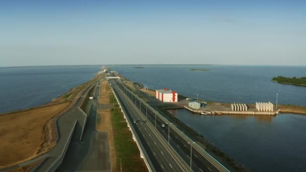 Airial rising shot of a highway and cars driving across the sea — Stok Video