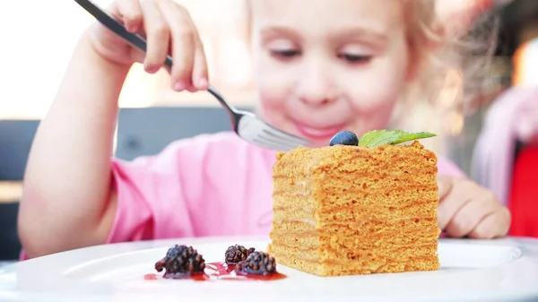 Menina feliz come bolo de mel com um garfo — Fotografia de Stock