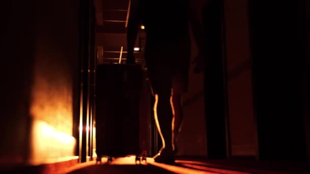 Slow motion opname van een onbekende man met zware koffer loopt in een zonnige hotelgang, verlaten of check out concept — Stockvideo