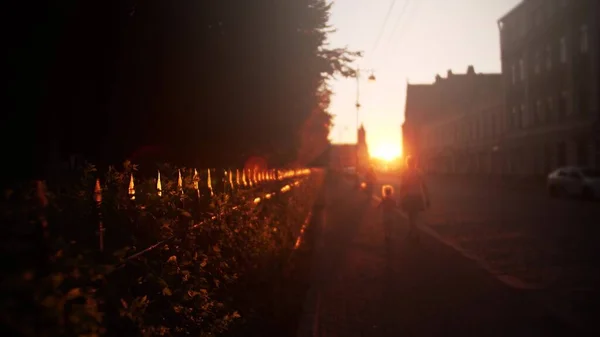 Wazig moeder en klein meisje lopen langs de zonovergoten straat in de avond — Stockfoto