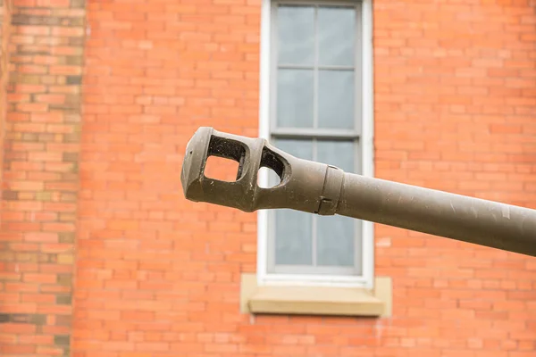 Armourd tank gun muzzle in front of red brick wall — Stock Photo, Image