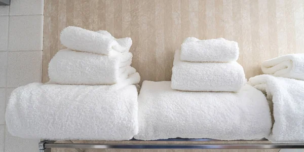 Белые полотенца сложены на стойке в туалете отеля — стоковое фото