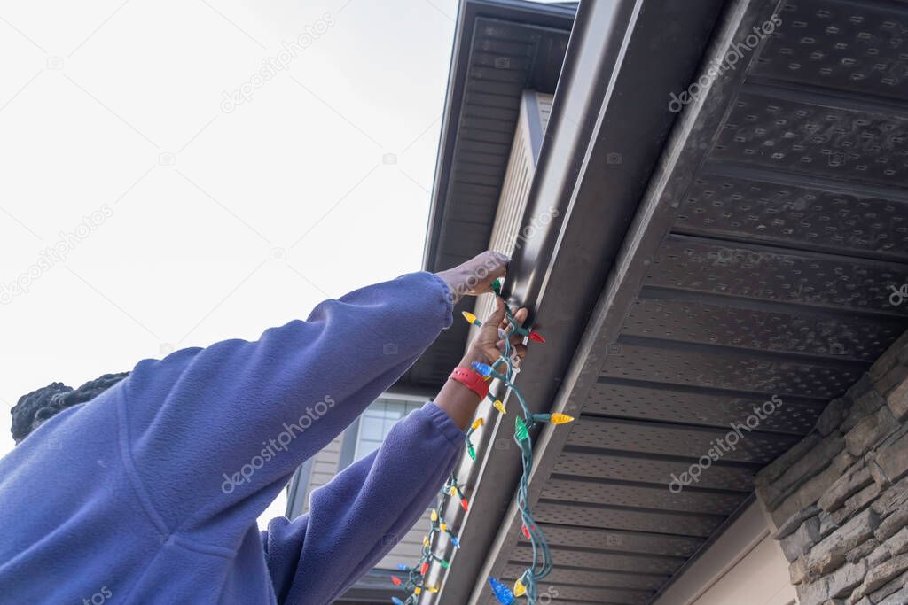 African American Nigerian Woman installing christmas lights